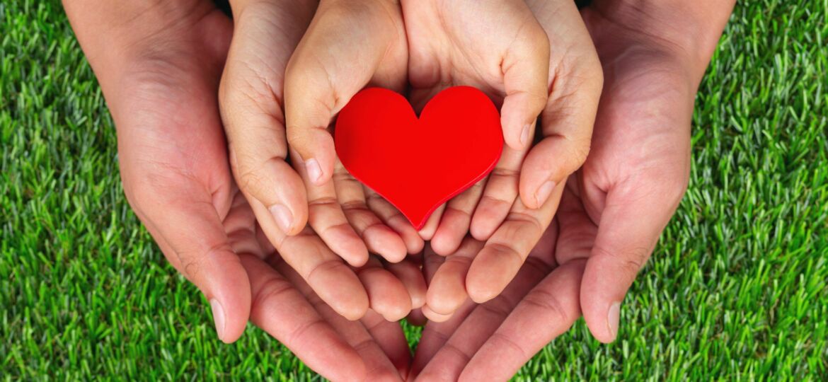 red heart shape in family member's hands holding