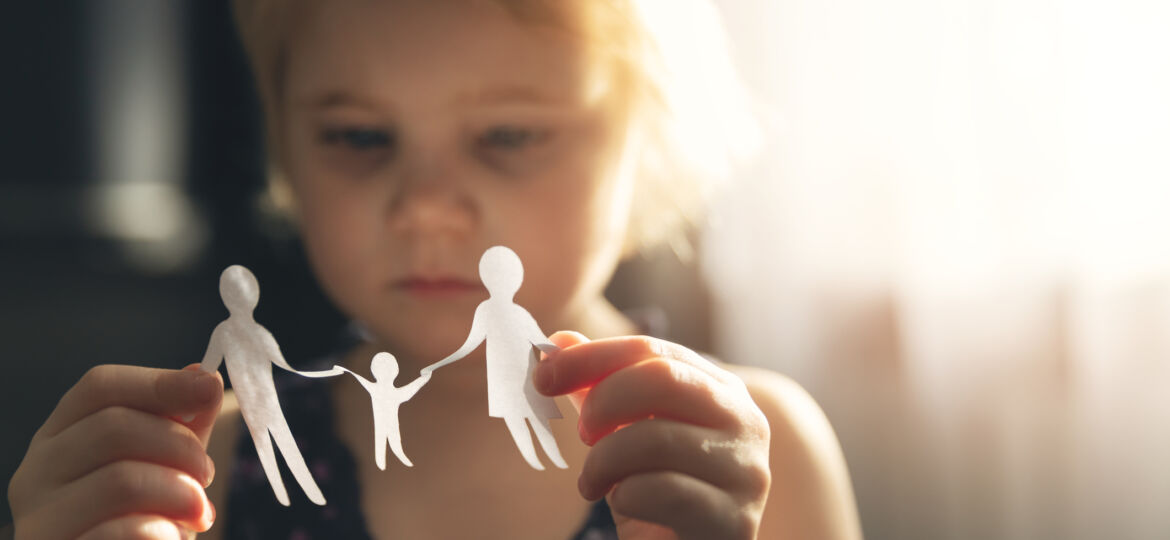 little girl with paper family in hands. concept of divorce, custody and child abuse